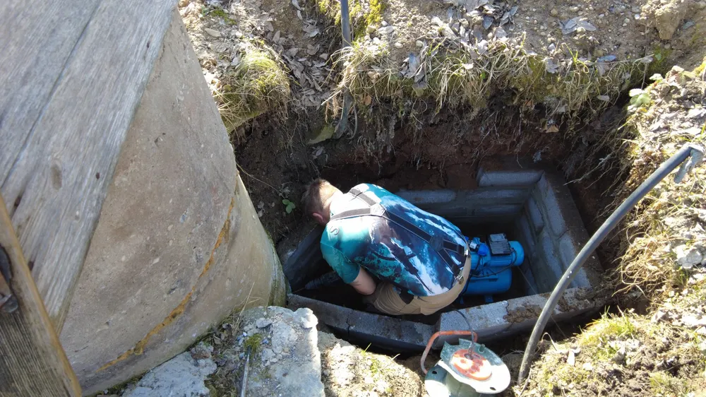 Technician working on a submersible well pump in a rural well pit — illustrative stock photo of pump service work, not an actual Pahrump job site