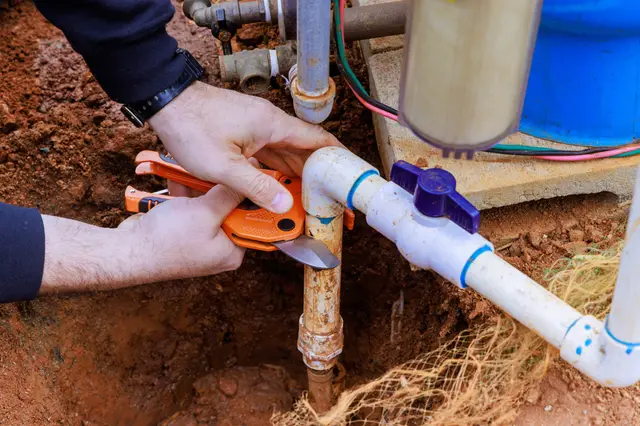 Technician's hands fitting a clamp on well pump piping — illustrative stock photo of pump maintenance work, not an actual Pahrump job site