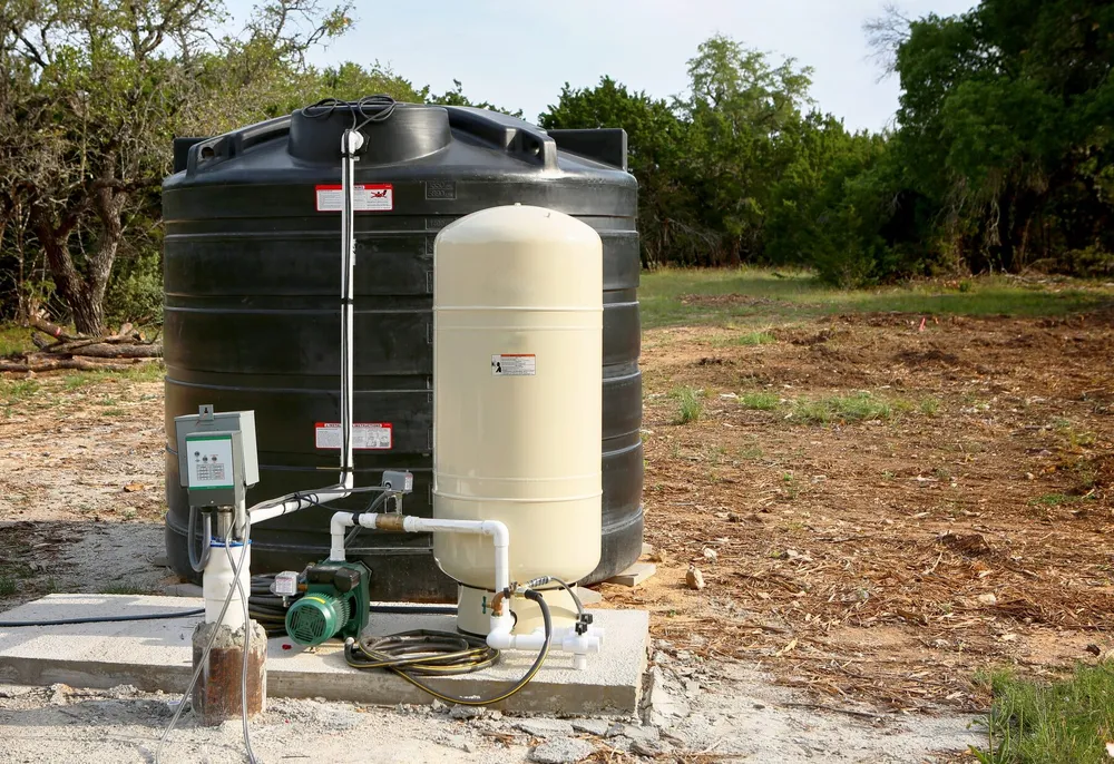 A poly water storage tank on a rural desert property — illustrative stock photo of a residential well setup, not an actual Pahrump property